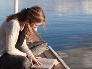 Chica leyendo junto al agua