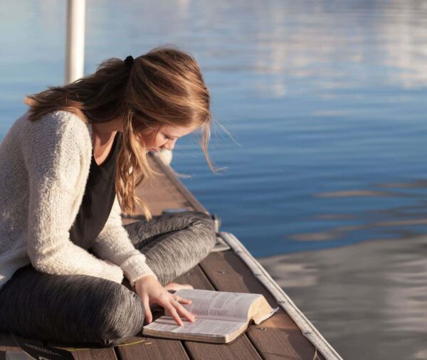 Chica leyendo junto al agua